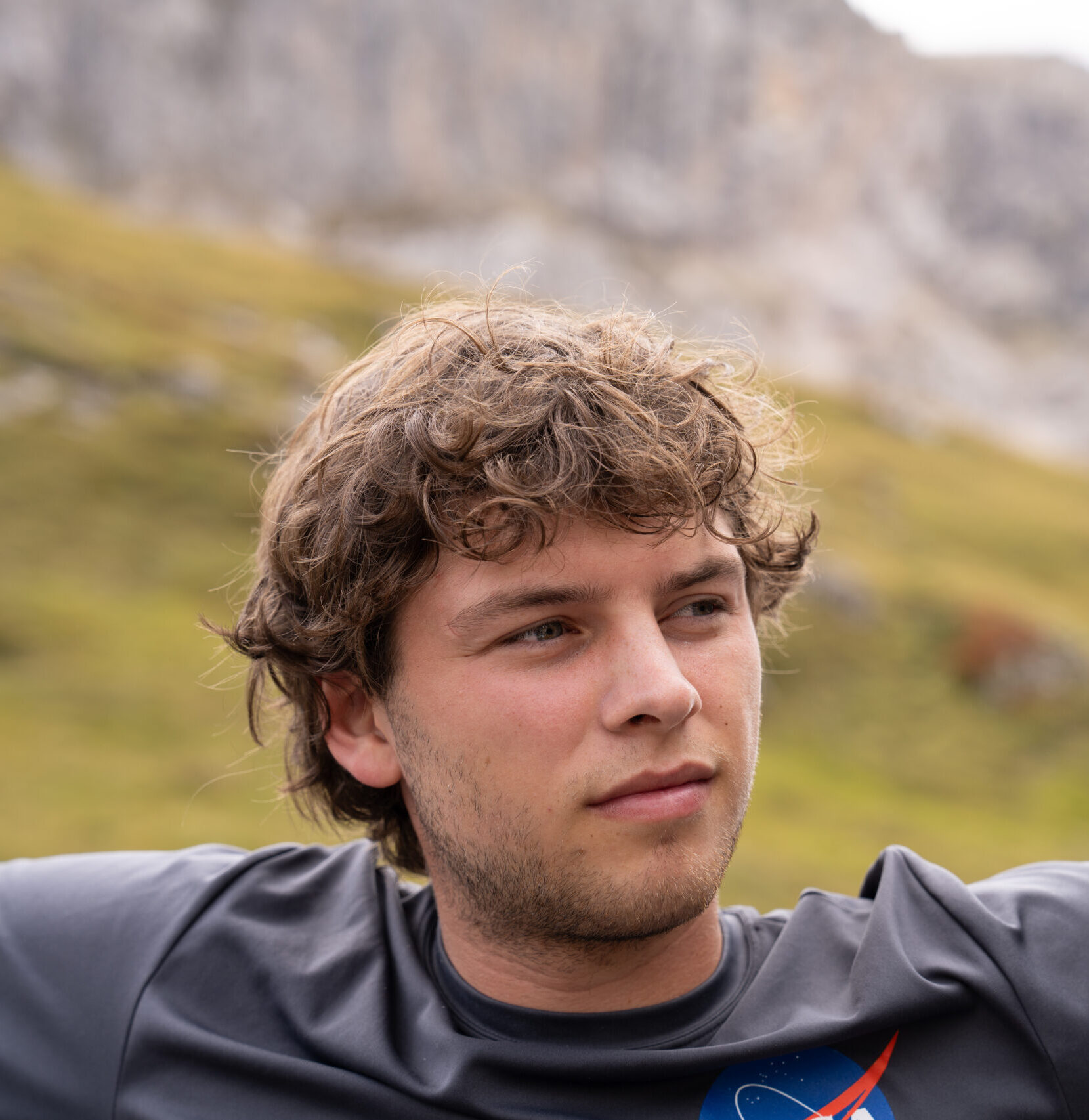 photo of Kieran looking out to the right, with mountain and grassy hills in background