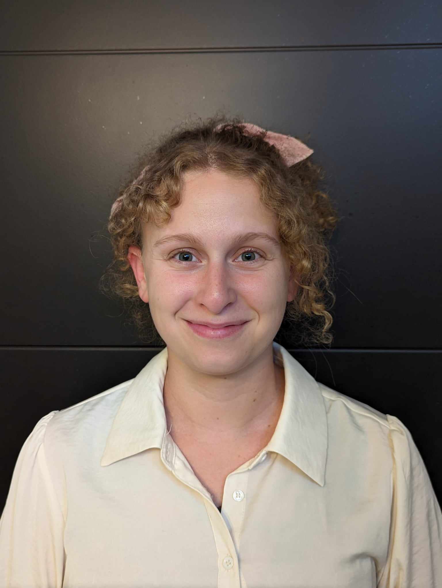 Photo of Adina with white collared short, blonde curly hair and pink hair ribbon